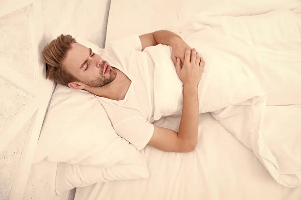 Duerme en la cama. madrugada despierta. hombre durmiendo dormitorio blanco. acogedor fin de semana en casa. tiempo para relajarse. tipo se duerme. concepto de salud masculina. tener un sueño. Concepto de tranquilidad — Foto de Stock