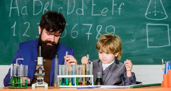 Jeder ist ein Leistungsträger. Schulungsraum mit Tafel. Kolben in der Hand mit Reagenzgläsern. Weisheit. Zurück zur Schule. Sohn und Vater in der Schule. Kleiner Junge mit Lehrer — Stockfoto