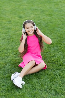 Yaz şarkı listem. Dışarıda dinlenirken müzik dinlemek. Eğitici podcast. Çocuk yeşil çayır müziğinin tadını çıkarıyor. Keyifli zaman. Çocuk kulaklıkları müzik dinler. Kız kulaklıkları müzik dinliyor.