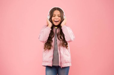 Müzik neşe verir. Mutlu çocuk pembe arka plan müziği dinle. Küçük kız müzik çalarken kulaklık takıyor. Çocuklar için yeni teknoloji. Eğlence ve eğlence. Modern yaşam tarzı. Müzik hayattır.