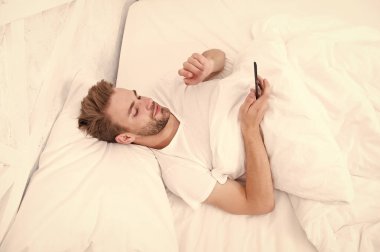 Sabahtan beri akıllı telefon kullanıyor. Tüm dünya telefonda. Blog yazıyor. Flört ediyor ve mesaj yolluyor. İnternet bağımlılığı ve mobil taciz kavramı. Adam yatakta sohbet ediyor.