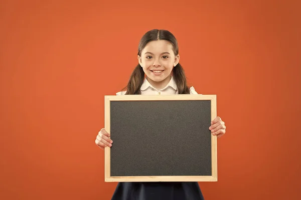 Concepto de banner. pizarra para espacio de copia. información. escribir hometask. de vuelta a la escuela. Feliz día de los maestros. 1 de septiembre. Muchacha pequeña demostrar anuncio. niña de la escuela pequeña feliz con pizarra — Foto de Stock