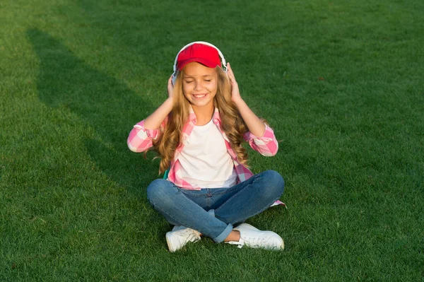 Rahatlatıcı ses. Mutlu çocuk dışarıda müzik dinler. Küçük kız kulaklıkla müzik dinlemeyi sever. Hi-Fi stereo sesi. Ses ve müzik teknolojisi. Modern hayat. Rahatlamanın yeni bir yolu — Stok fotoğraf