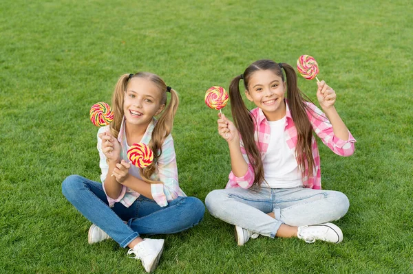 Chicas dulces. Los niños felices sostienen la hierba verde caramelo. Tienda de dulces. Paleta o chupetón en palos. Dulces azucarados. Fábrica de dulces y confitería. Dulce sueño — Foto de Stock
