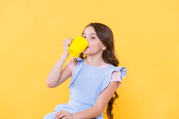 No es mi taza de té. Haciendo sorbos. Bebe suficiente agua. Niña sostiene la taza de fondo amarillo. Un niño encantador sostiene la taza. Beber cacao de jugo de té. Relajarse con la bebida. Bebida infantil. Hábitos saludables —  Fotos de Stock