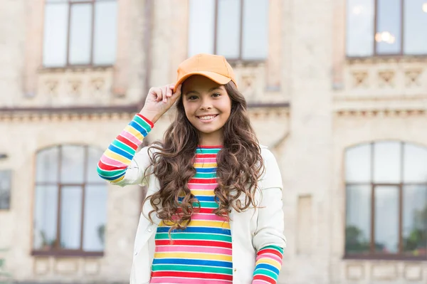 Criança sorrindo ao ar livre. Beleza e moda. Não saberias de nada se não tentasses. A estudante usa boné. Adolescente em estilo casual e boné. Felicidade infantil. Menina feliz com cabelo encaracolado usando boné — Fotografia de Stock