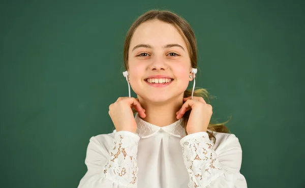 Kształcenie domowe w internecie. Dziewczyna w słuchawkach słuchająca muzyki. Słuchanie audiobooka. Uczennica w słuchawkach w tle tablicy. Tłumaczenie audio. Koncepcja uczenia się audio — Zdjęcie stockowe