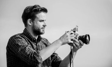 Adam açık havada gökyüzü arka planında. Antika ekipmanlar. Blogger video blogu çekiyor. Tatil zamanı. Yakışıklı blogcu, gezgin, geçmişe dönük kamera. Fotomuhabir konsepti. Gezgin blogcu. Gazeteci fotoğraf çekiyor.