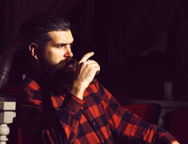 Sakallı hippi, kareli gömlek içinde viski bardağı taşıyor.