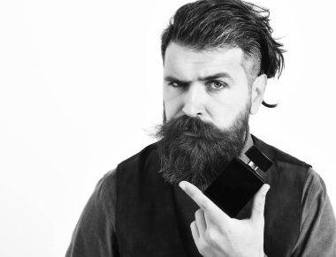 Sakallı adam ciddi bir parfüm tutuyor.