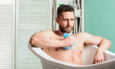 Köpüğü dikkatlice suyla yıka. Maço banyo yapıyor. Banyodaki seksi adam. Adam kaslı vücudu süngerle yıkıyor. Küvette çıplak maço. Seks ve rahatlama konsepti. Erotik fantezi