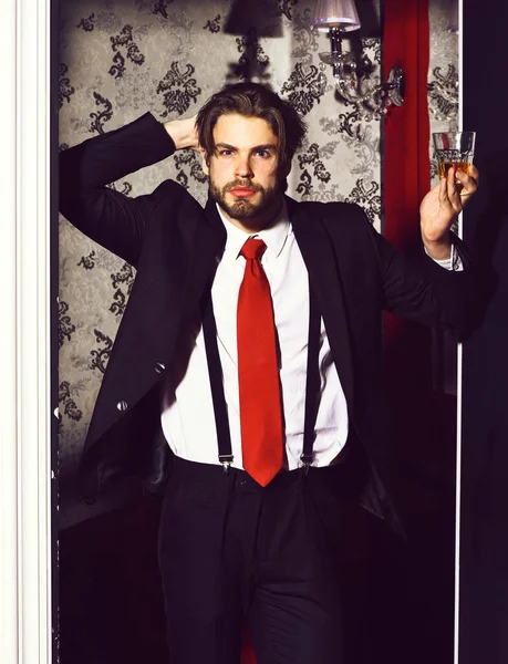Vousatý muž, obchodník v obleku, červená kravata drží sklenici whisky — Stock fotografie