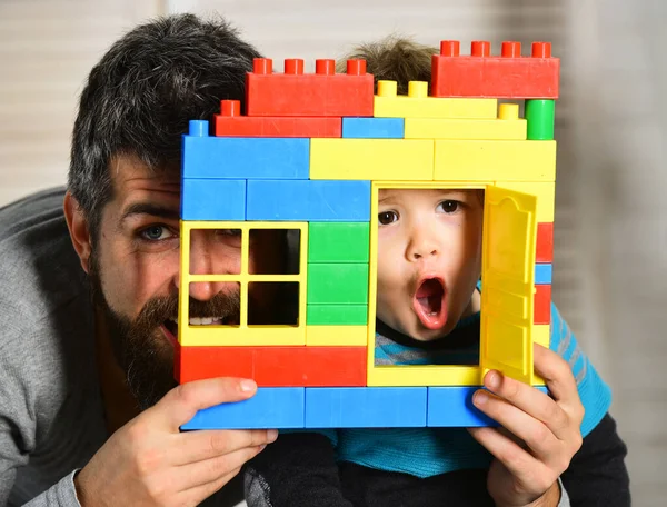 Vater und Sohn blicken mit überraschten Gesichtern durchs Fenster — Stockfoto