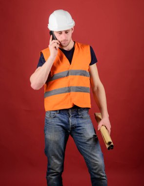 Mühendis, mimar, elinde planlar varken akıllı telefondan konuşuyor. Adamım, miğferli ustabaşı telefonda konuşuyor, kırmızı arka plan. İletişim konsepti. Mimardan, planı düzeltmesi için mühendise.