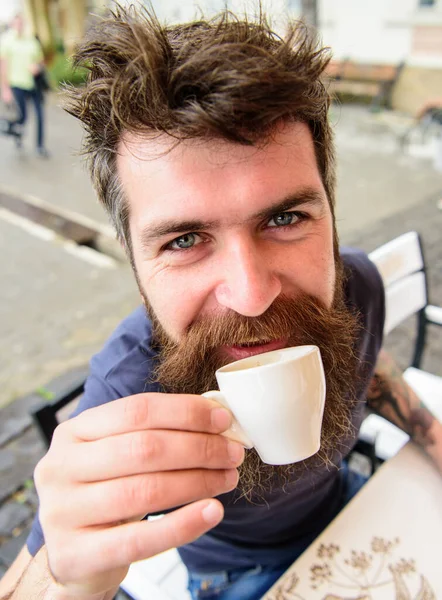 Hipster na cara alegre bebendo café ao ar livre. Homem com barba e bigode segura xícara de café enquanto relaxa no terraço do café. Um tipo a descansar com café expresso. Conceito de coffee break — Fotografia de Stock