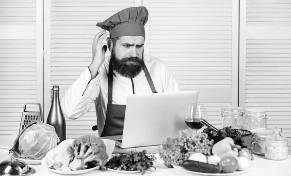 Culinary education online. Elearning concept. Man chef searching internet recipe cooking food. Chef laptop read culinary recipes. Culinary school. Hipster in hat and apron learning how to cook online