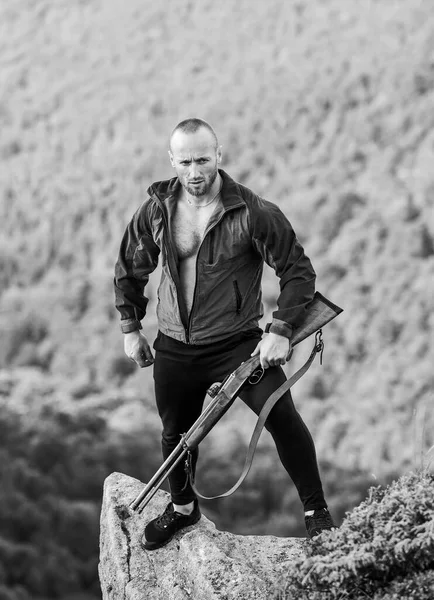 Hunter caçador furtivo à procura de vítima. Caçador com rifle ambiente natureza. Caça ilegal. Poacher stand on edge of cliff. Conceito de caça furtiva. Homem brutal caçador furtivo com arma paisagem natural fundo — Fotografia de Stock