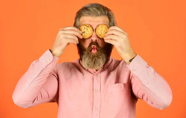 Obcecado por pastelaria. Doces biscoitos. Conceito de dente doce. Bolachas na cabeça dele. Homem barbudo segura biscoitos nos olhos. Deliciosos petiscos deliciosos. Receita biscoitos caseiros. hipster feliz comer sobremesa de biscoitos — Fotografia de Stock