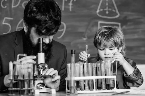 Flask in scientist hand with Test tubes. Wisdom. Back to school. small boy with teacher man. son and father at school. training room with blackboard. Education is a superior shield of freedom. — Stockfoto