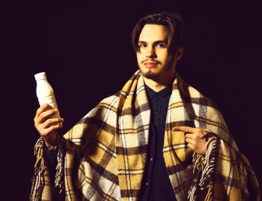 Siyah stüdyo geçmişinde ekoseli sakallı, gülümseyen bir adam.