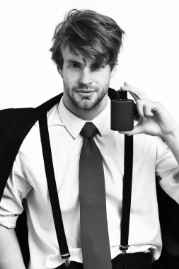 Beyaz arka planda parfümle poz veren Kafkas tarzı bir adam.