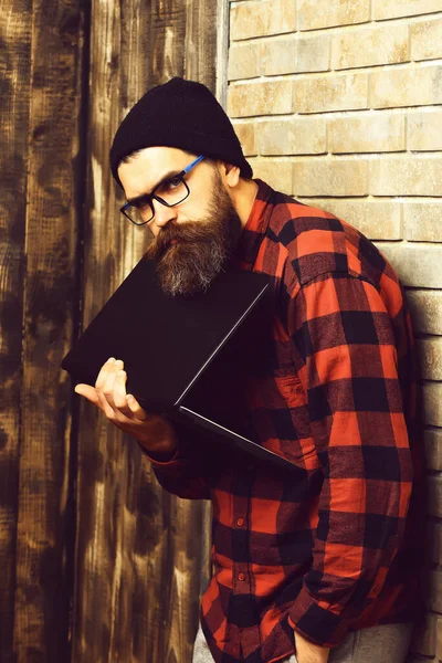 Skägg brutal kaukasiska hipster håller laptop på beige tegel vägg studio bakgrund — Stockfoto
