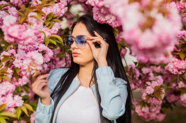 Bahar güneşinin tadını çıkarıyorum. Mutlu Paskalyalar. Seksi kız sakura çiçeğinin tadını çıkarıyor. Kiraz çiçekli kadın. Doğada yaşayan bir kadın. Kiraz çiçeklerinin bahçesindeki güzel genç bayan. 8 Mart