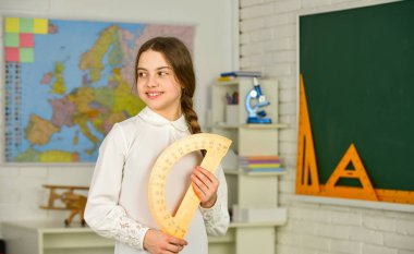 Geometri seti. Geometri dersi için okul ekstraktörü tutan küçük bir kız çocuğu. İletki kullanmayı öğreniyorum. Okula dönüyorum. Lise öğrencisi sınıfta geometri öğreniyor. derece cinsinden ölçün