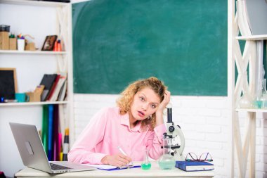 Öğretmenlik stresli bir uğraş. Basınç gerginliği. Stresli eğitimci. Kız, dizüstü bilgisayar ve mikroskop ile stresli ifadelerden sıkılmış biyoloji ve kimya araştırmaları yapıyor. Stresli bilim adamı