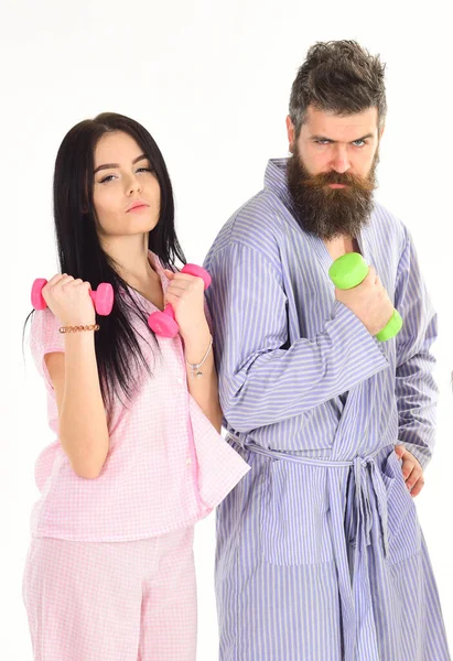 Sporty lifestyle concept. Girl and man with dumbbells, morning exercises. Couple in love in pajama, bathrobe stand isolated on white background. Couple, family do sports in morning, full of energy. — Stock Photo, Image