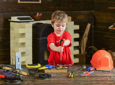El sanatları sınıfındaki sevimli çocuk. Tahtaya vida bağlayan çocuk. İki eliyle tornavida tutan küçük bir tamirci.