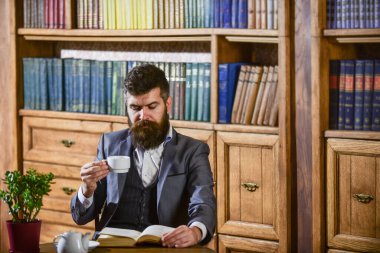 Eski kafalı adam elinde çayla bardak tutuyor. Klasik takım elbiseli adam.