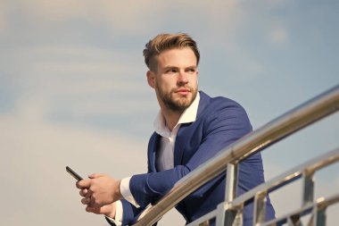 Ortağından önemli bir telefon bekliyorum. İş adamı video görüşmesi veya gökyüzü geçmişi için akıllı telefon kullanır. Takım elbiseli iş adamı modern mobil teknolojilerden iş için faydalanıyor.