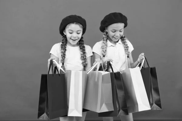 Kinderen tevreden met winkelen rode achtergrond. Geobsedeerd door winkels en kledingwinkels. Winkelverslaafd concept. Winkelen wordt leuk met beste vrienden. Kinderen schattig schoolmeisjes houden bos boodschappentassen — Stockfoto