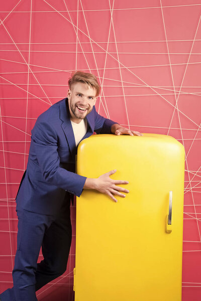 Мужчина формальный элегантный костюм стоять рядом с ретро винтажный желтый холодильник. Винтажные бытовые приборы. Голодный холостяк думает, что ест возле холодильника. Яркий холодильник бытовой техники