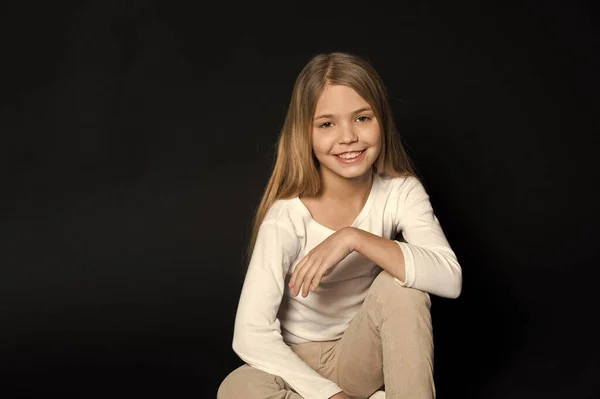 Criança feliz com penteado de moda no fundo preto. Menina sorrir com cabelo loiro longo. Menina beleza sorrindo com olhar adorável. Salão de beleza. Mantenha a calma e faça o seu cabelo — Fotografia de Stock