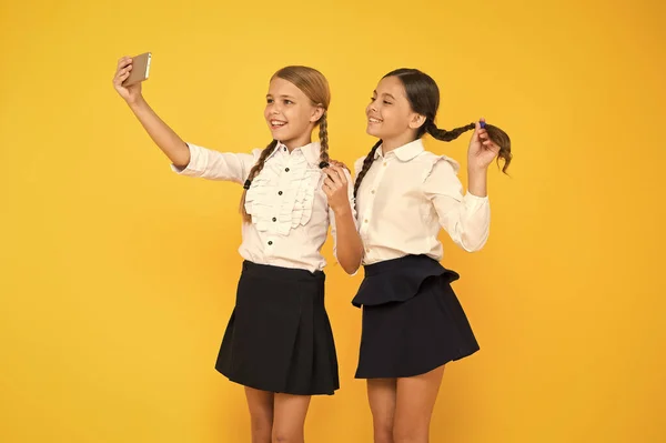 Mais uma selfie. Alunos felizes tirando selfie com smartphone no fundo amarelo. Meninas sorrindo para selfie câmera no celular. Sessão de selfie em 1 de setembro — Fotografia de Stock