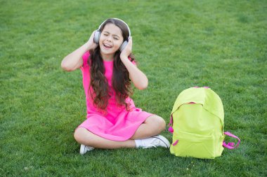 Müzik dinleyen kulaklıklar. Keyifli zaman. Çocuk kulaklıkları müzik dinler. Modern teknoloji. Liseli kız melodiyi sever. Açık havada dinlenen müziği dinle. Çocuk kız yeşil çayır müziğinin tadını çıkarıyor.