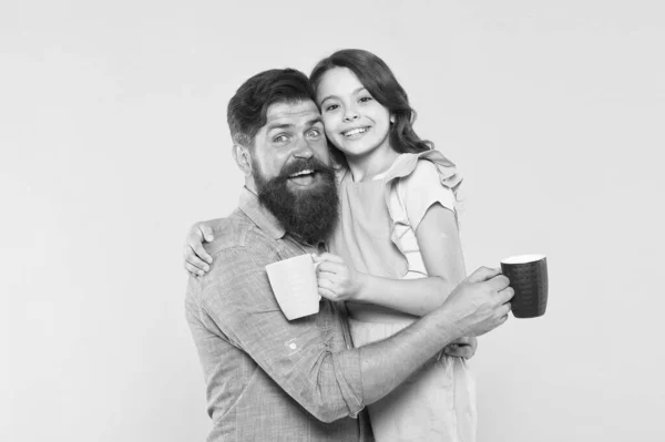 Bebe agua. Bebe jugo fresco. Concepto de desayuno. Buenos días. Tomando café juntos. Hermosa tradición familiar. Beber té. Hombre barbudo y chica feliz sosteniendo tazas. Padre e hija bebida caliente — Foto de Stock