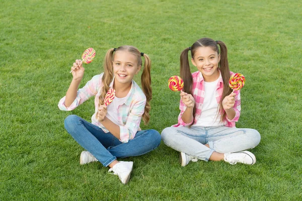 Disfruta de estas piruletas con sensación de sabor. Los niños felices sostienen piruletas hierba verde. Comer grandes piruletas remolino en palos. Tienda de dulces. Disfrutando de piruletas con sabores a frutas. Sabroso y delicioso — Foto de Stock