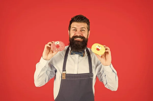 Livraison de beignets. boulanger habile avec beigne. drôle beignet de cuisinier hipster. tentation pendant le régime. boulangerie masculine. homme barbu dans tablier de chef. serveur brutal sur la cuisine. mature homme rouge fond — Photo