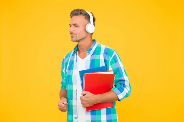 Estudia idiomas. Cursos gratuitos. Cursos de audio. Aprendiendo inglés. Tecnología moderna. Concepto de audio libro. Acceso mundial al conocimiento. Biblioteca de audio. Hombre guapo estudiante usar auriculares mantenga libros —  Fotos de Stock