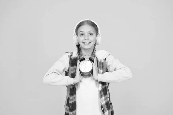 Chica hipster manejar el tiempo correctamente. colegiala estilo casual celebrar reloj despertador retro. período de educación de otoño. niño escuchar auriculares de música. gestión del tiempo en la infancia. examen plazo concepto —  Fotos de Stock