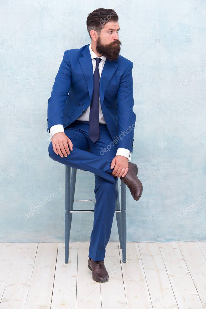 Elegante y formal. El hombre barbudo usa traje formal. Elegante abogado sentado en la silla. Vestirse