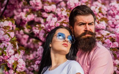 Kiraz ağacının pembe çiçekleri. Aşık bir adam ve kadın. Bahar günü filizlenen dalların altında sevgi dolu bir çift. Çiçek açan bahçede eğlenen bir çift. Kiraz çiçekli kadın ve erkek