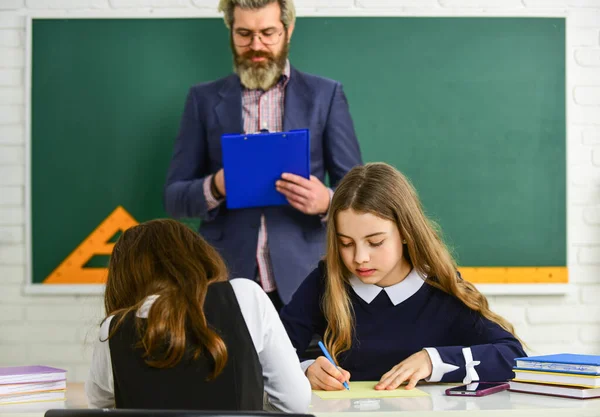 Probando estudiantes. Pedagogo. Mirándolos. Aula de profesores y niños. La vida escolar diaria. De vuelta a la escuela. Ayuda y apoyo. Niños y maestros. Estudiantes enfocados y concentrados. Proceso de control — Foto de Stock