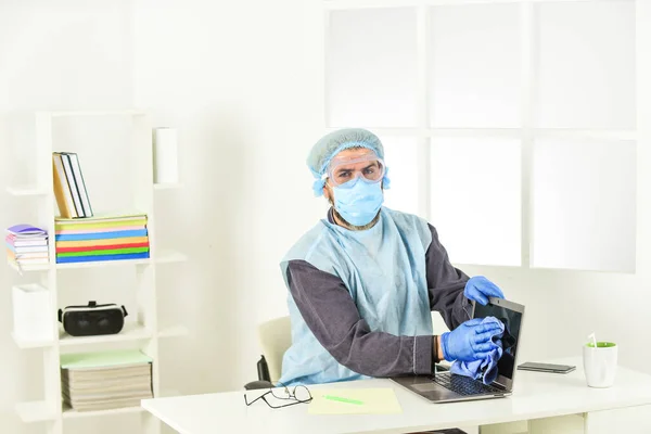 Risk being exposed coronavirus. Worker disinfecting computer. Clean frequently touched surfaces. Personal hygiene. Cleaning and Disinfection. Wearing mask protect from coronavirus. Serious hygiene