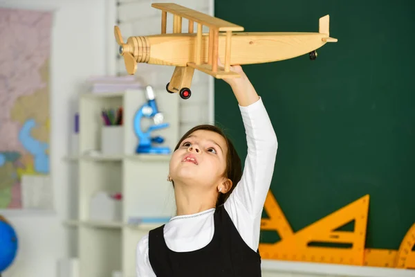 Śnij dalej. Uczennica grać drewniany samolot zabawki. Leć samolotem. Studiuj geografię. Na całym świecie. Sny o podróżach. Wracać do szkoły. Opowieść o wakacjach. Jak spędziłem lato. Podróż samolotem — Zdjęcie stockowe
