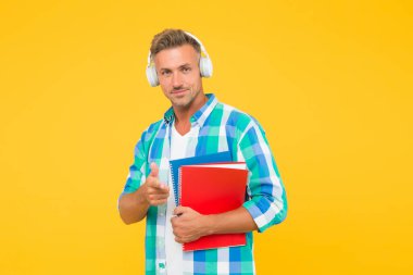 Yakışıklı üniversite hocası işaret ediyor. Yetişkin öğrenci not defterini tutuyor. Kulaklıklı klasörlü adam. Online eğitim. Adam kitap okurken not almak için elinde kitap tutuyor. Not defterine yazalım.