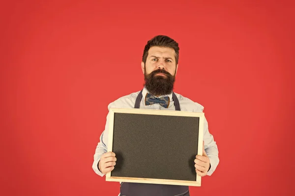 Urgente para comer. Blogger de comida. barman hipster serio. Qué cocinar. Menú del restaurante. anuncio de la tienda de café. hombre barbudo pizarra, espacio de copia. camarero brutal en la cocina. maduro hombre rojo fondo — Foto de Stock